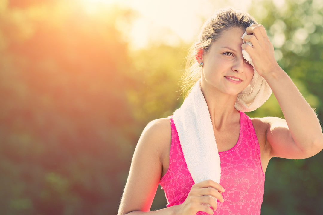 A woman is wiping sweat from her forehead with a towel on a hot day