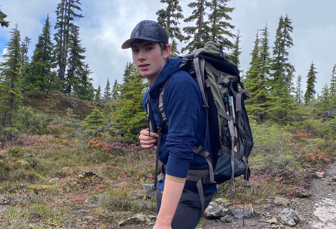 A young man is hiking while wearing a Polartec Alpha Direct hoodie