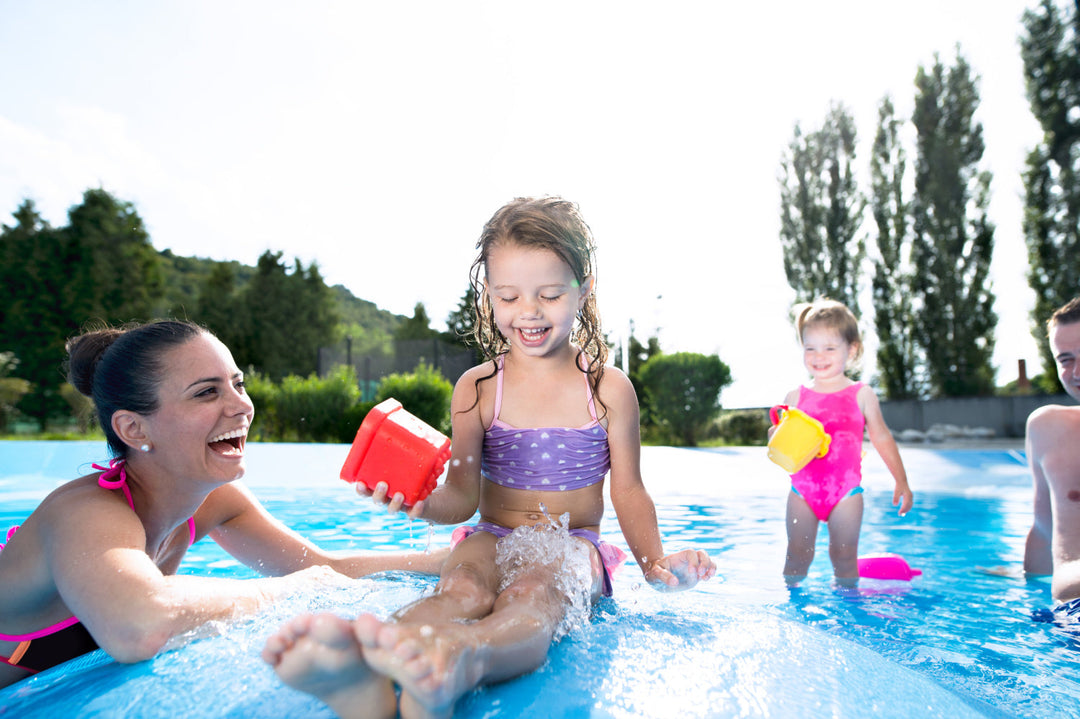 Young family in swim suits playing in a pool