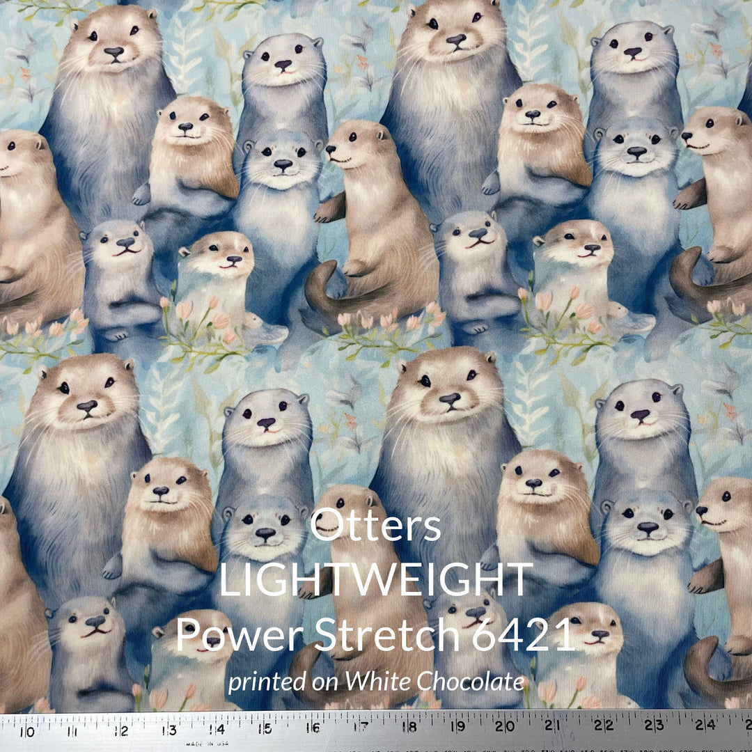 A cute print of otters in shades of tan taupe grey and blue on a water colour blue background printed on polartec power stretch fleece