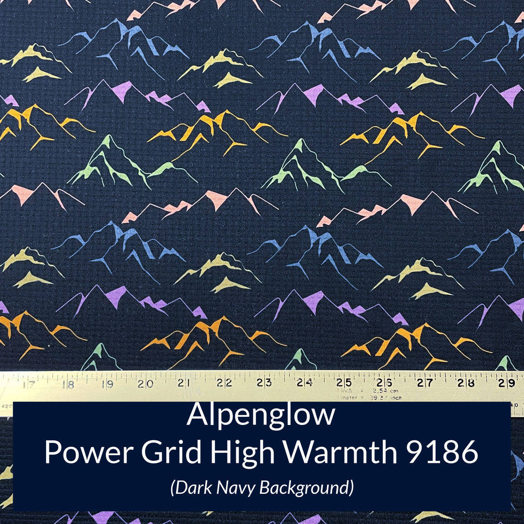 a print on polartec power grid high warmth fabric with a navy background and outlines of mountain ridges in shades of green blue orange and pink