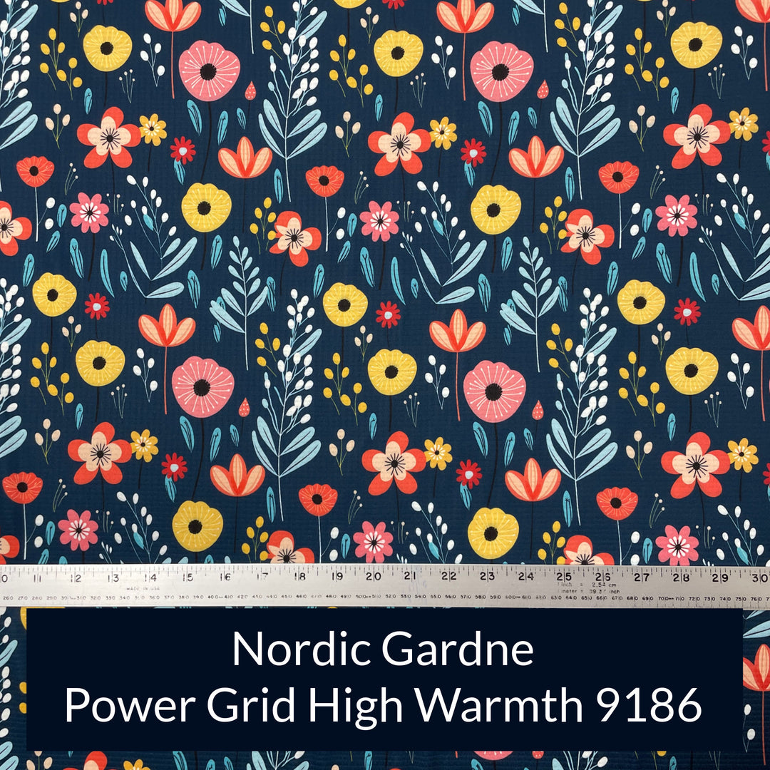 a print on polartec power grid high warmth fabric with a dark navy background with nordic style flowers and berries in shades of orange peach yellow aqua and ablue
