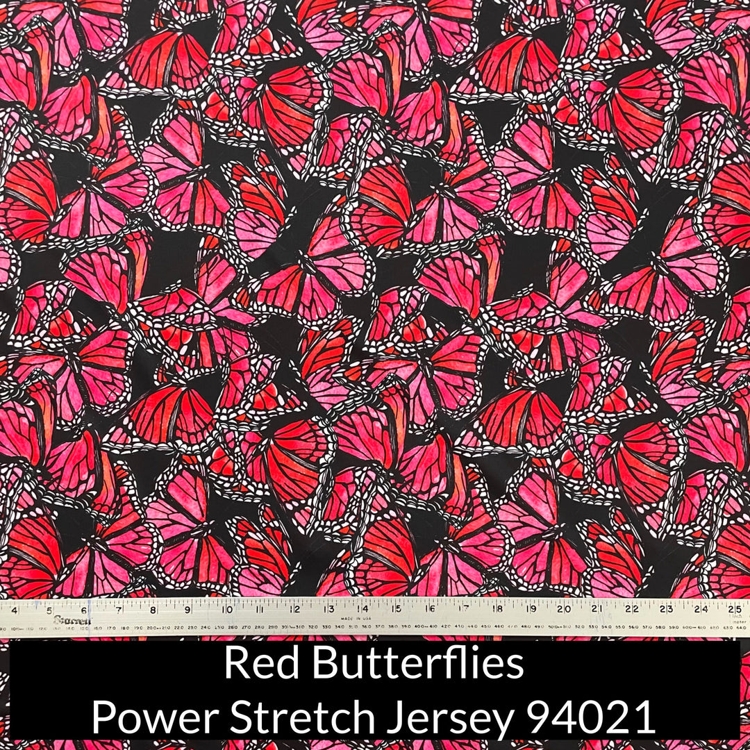 an abstract pattern of watercolour painted red and pink monarch design butterflies on a black background on power stretch jersey fabric