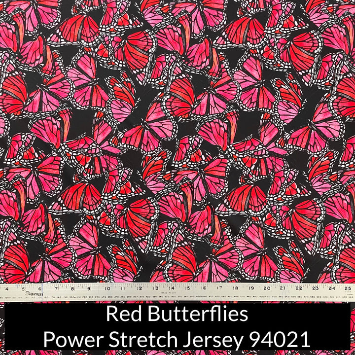 an abstract pattern of watercolour painted red and pink monarch design butterflies on a black background on power stretch jersey fabric