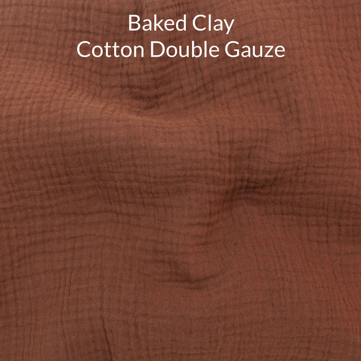 Close-up of a mid brown colored cotton double gauze fabric with text overlay noting the colour name is baked clay.