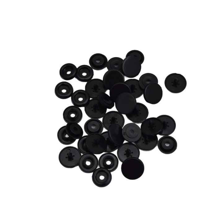 A pile of small black plastic snap component pieces, photographed on a plain white background.