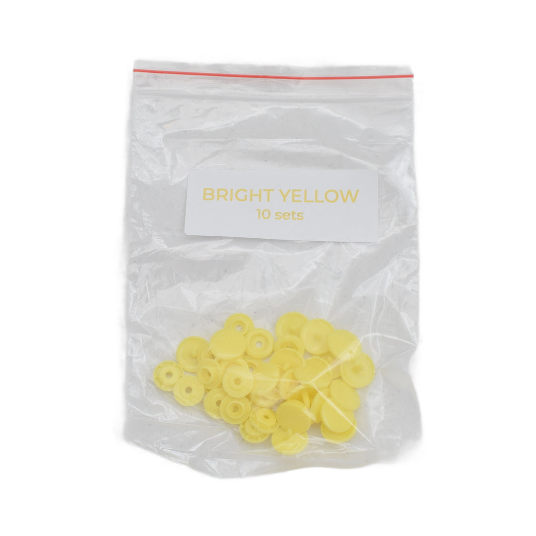 A clear plastic zip-top bag labeled 'BRIGHT YELLOW 10 sets' containing small bright yellow circular plastic snap pieces, shown on a white background.