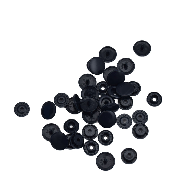 A pile of small dark navy plastic snap components scattered on a plain white background.