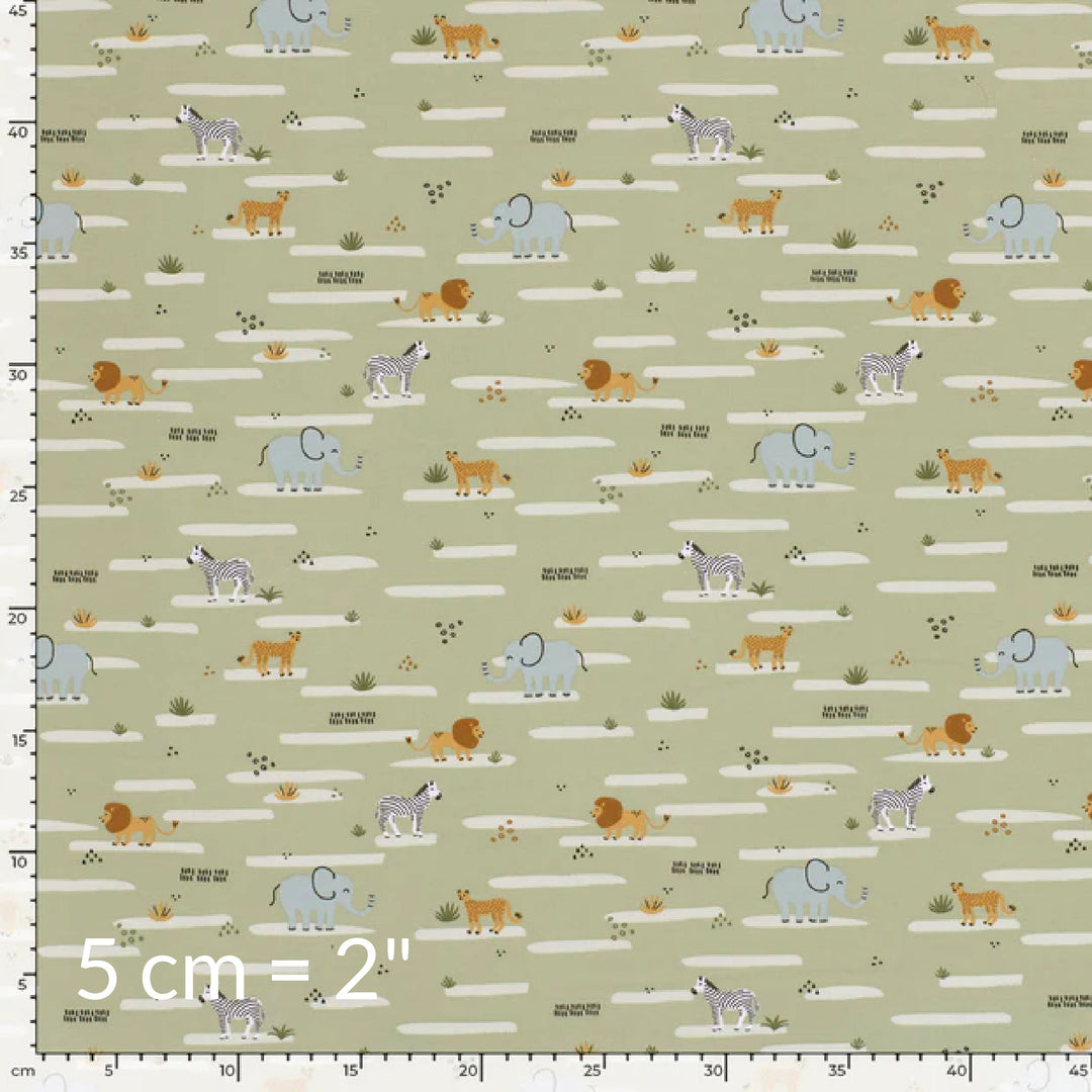 Fabric swatch showing cute children's print of African animals on a pale olive green background with ruler for scale