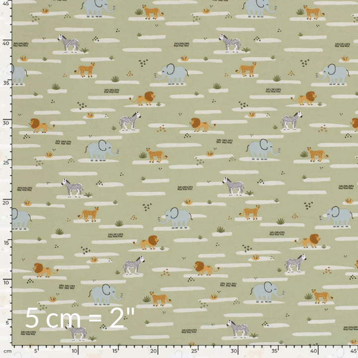 Fabric swatch showing cute children's print of African animals on a pale olive green background with ruler for scale