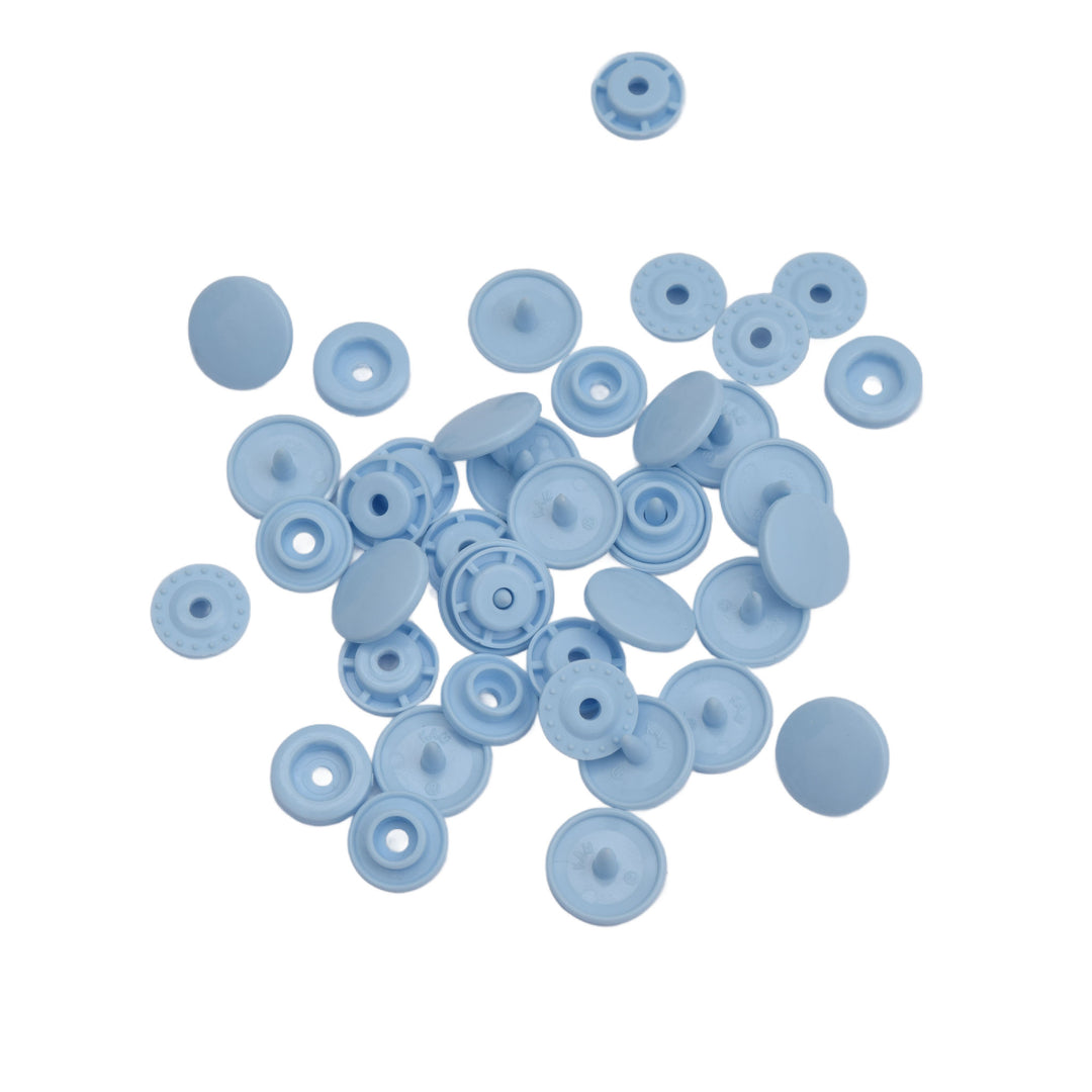A pile of small light blue plastic snap components on a plain white background.