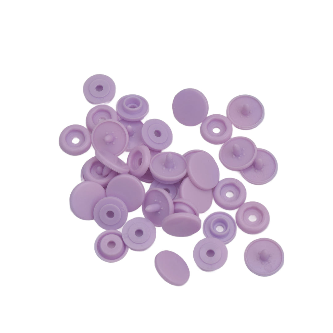 A pile of small lilac plastic snap components on a plain white background.