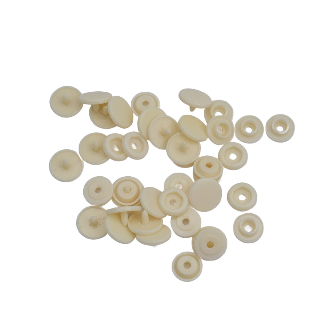A pile of small round off-white plastic snap components, scattered on a plain white background.