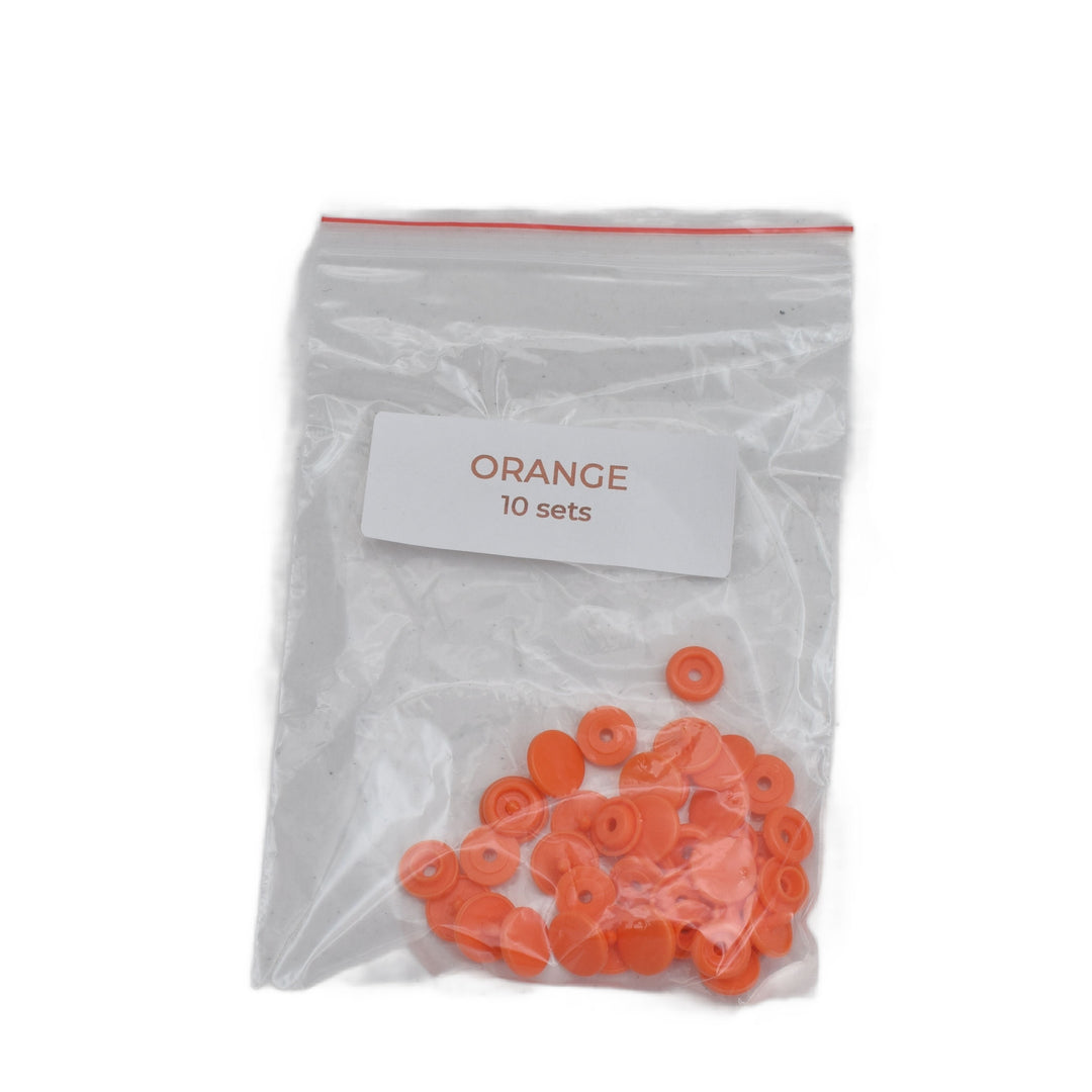 A clear plastic zip-top bag containing 10 sets of small orange circular size T5 round plastic snaps, with a white label reading 'ORANGE 10 sets' on a plain white background.