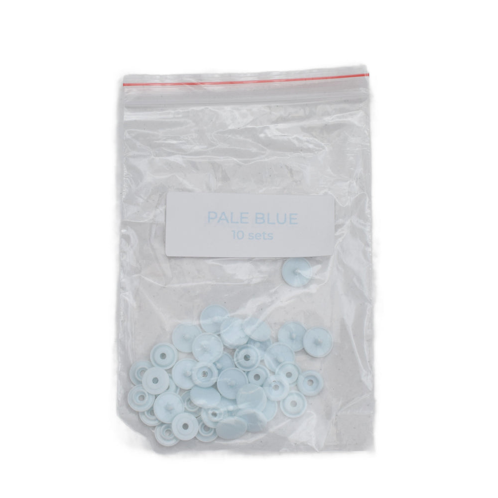 A clear plastic zip-top bag containing size T5 pale blue round plastic snaps, with a white label reading 'PALE BLUE 10 sets' on a white background.
