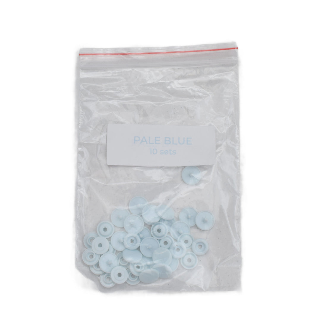 A clear plastic zip-top bag containing size T5 pale blue round plastic snaps, with a white label reading 'PALE BLUE 10 sets' on a white background.