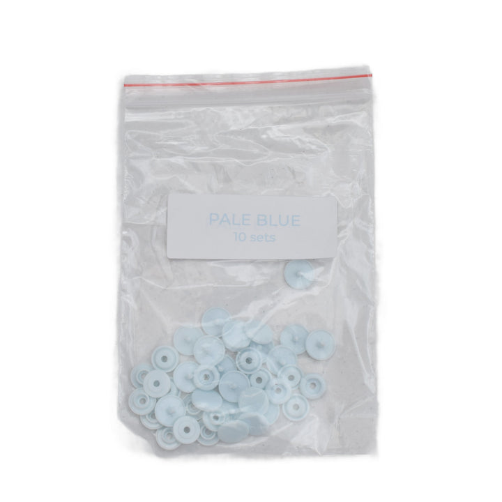 A clear plastic zip-top bag containing size T5 pale blue round plastic snaps, with a white label reading 'PALE BLUE 10 sets' on a white background.