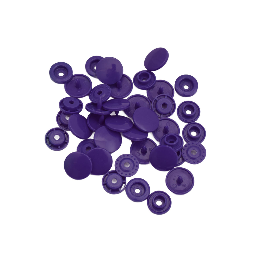 A pile of small purple plastic snap component pieces, shown on a plain white background.