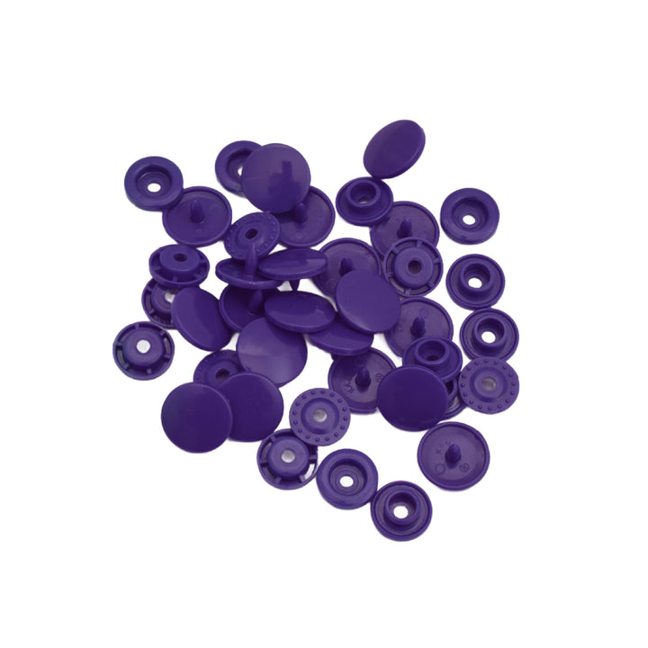 A pile of small purple plastic snap component pieces, shown on a plain white background.