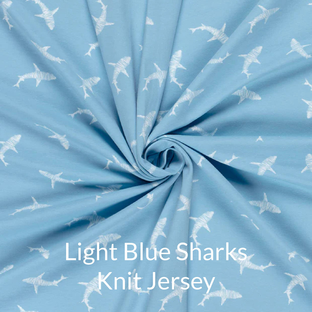 Fabric swatch of cute children's print of white sharks on a light blue background