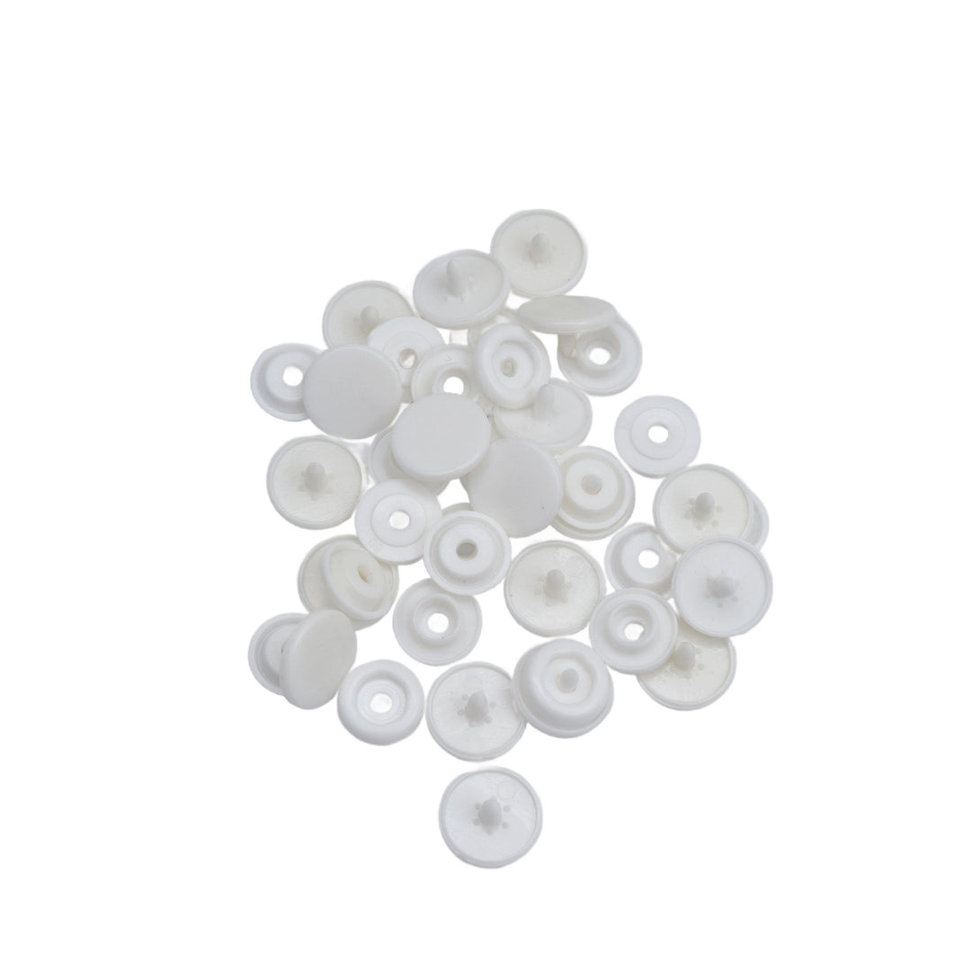 A pile of small white plastic snap components, photographed on a plain white background.