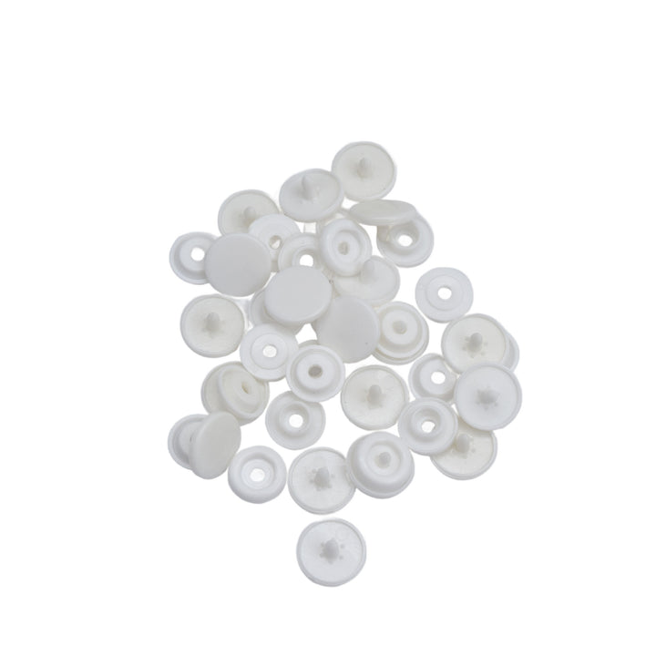 A pile of small white plastic snap components, photographed on a plain white background.