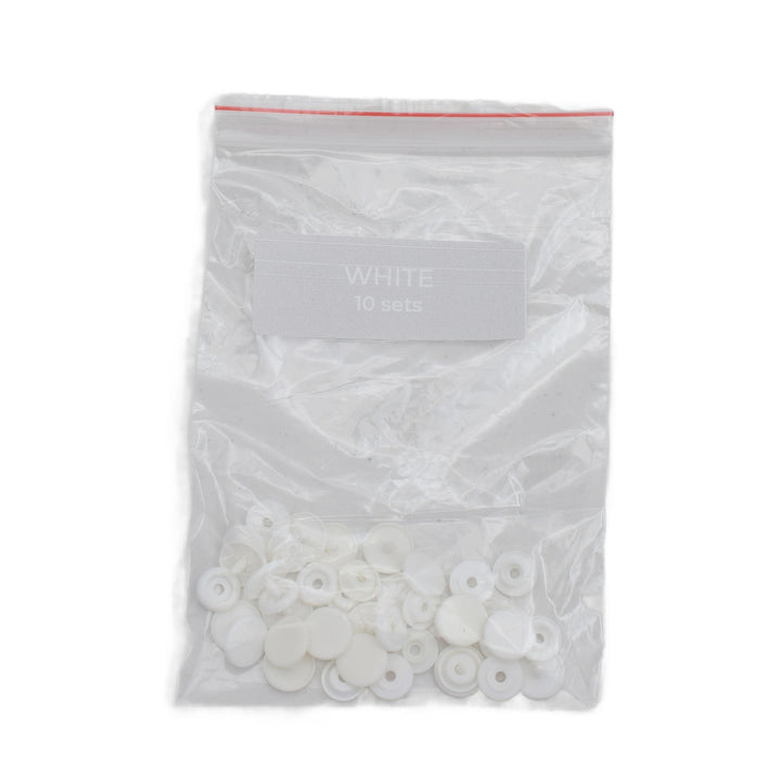 A clear plastic zip-top bag containing small white circular plastic snap pieces, with a label reading 'WHITE 10 sets' on a plain white background.