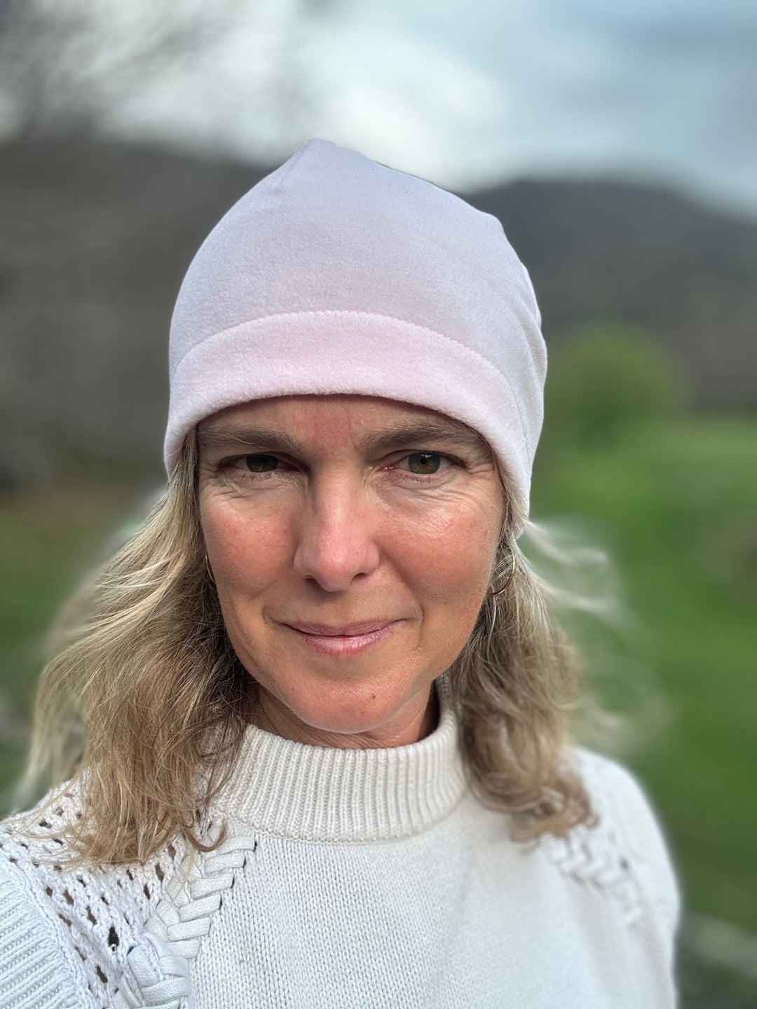 Head shot of woman standing outside wearing a pink beanie. Front view