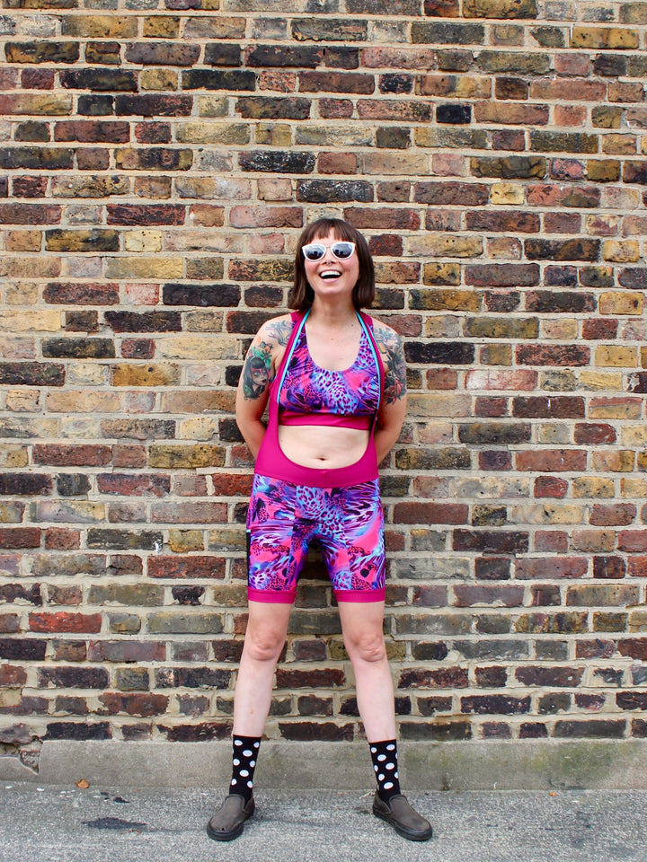 Rouleur Leggings view B - image of woman in brightly coloured bib shorts standing against a brick wall